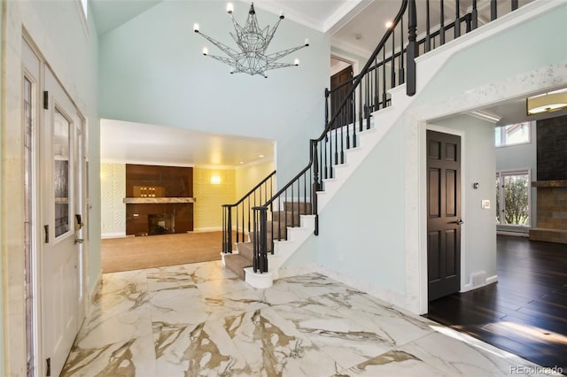 foyer with a high ceiling, ornamental molding, a chandelier, and hardwood / wood-style flooring