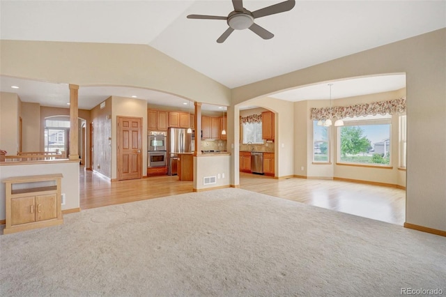 16231 Rayburn St, Hudson, CO 80642 - unfurnished living room featuring light carpet, lofted ceiling, arched walkways, and plenty of natural light