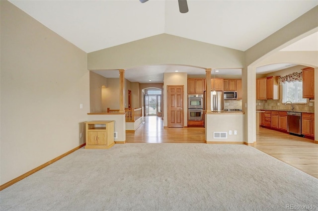 16231 Rayburn St, Hudson, CO 80642 - unfurnished living room featuring arched walkways, a ceiling fan, light colored carpet, vaulted ceiling, and baseboards