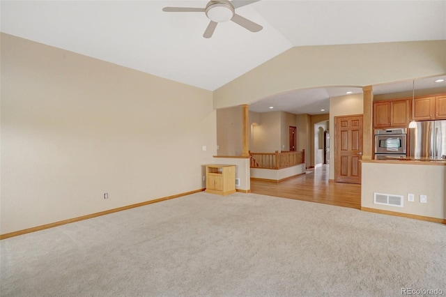 16231 Rayburn St, Hudson, CO 80642 - unfurnished living room featuring light colored carpet, lofted ceiling, arched walkways, a ceiling fan, and baseboards