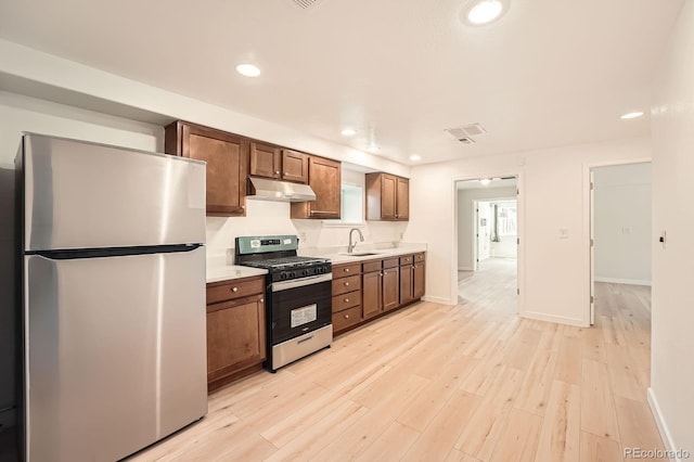 1533 E Harlan, Lakewood, CO 80214 - kitchen featuring stainless steel appliances, under cabinet range hood, light countertops, light wood-style flooring, and recessed lighting