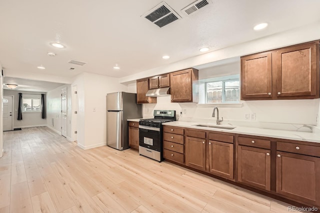 1533 E Harlan, Lakewood, CO 80214 - kitchen with stainless steel appliances, a sink, under cabinet range hood, light countertops, and light wood-type flooring