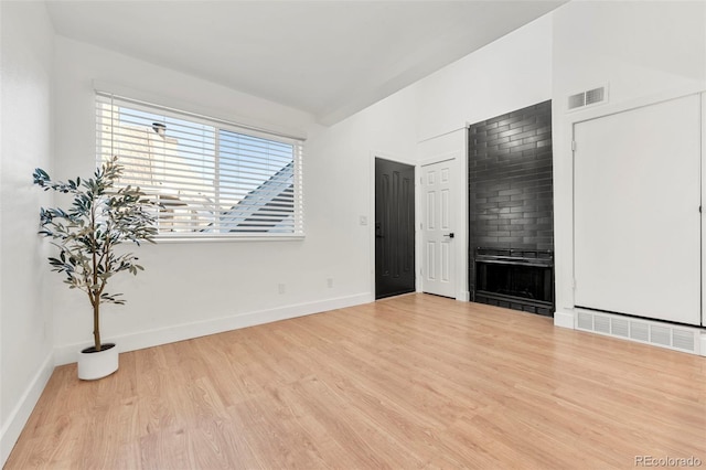 spare room featuring a large fireplace and light hardwood / wood-style flooring