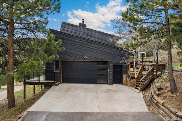 6640 Kilimanjaro Dr, Evergreen, CO 80439 - view of side of home featuring concrete driveway, a deck, an attached garage, and a chimney