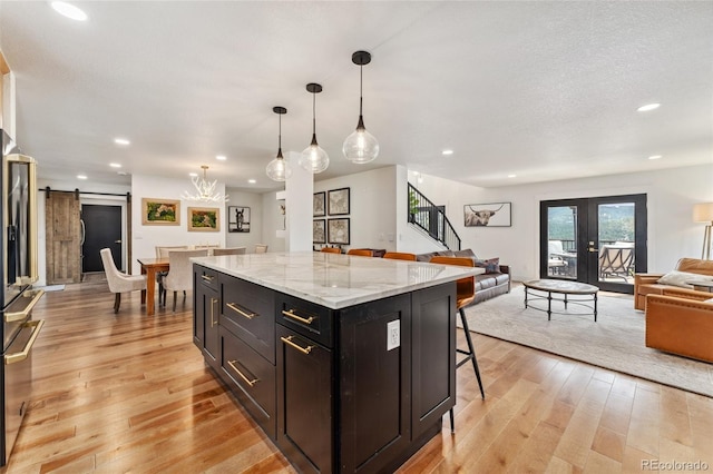 6640 Kilimanjaro Dr, Evergreen, CO 80439 - kitchen with a kitchen island, light wood-style floors, open floor plan, a kitchen bar, and a barn door