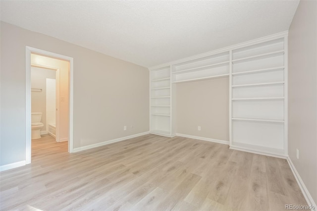 unfurnished bedroom with light wood-type flooring and a textured ceiling