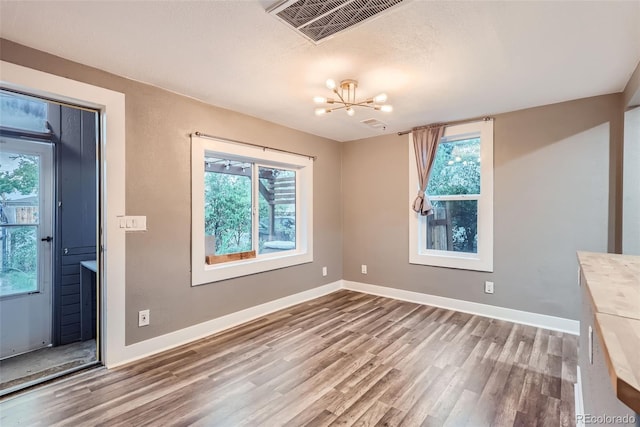 unfurnished dining area with hardwood / wood-style floors and a chandelier