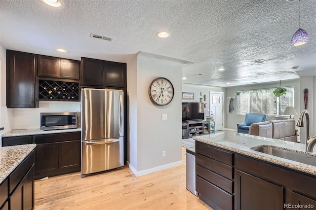 2901 N Glencoe St, Denver, CO 80207 - kitchen featuring stainless steel appliances, a sink, a textured ceiling, light wood finished floors, and dark brown cabinets