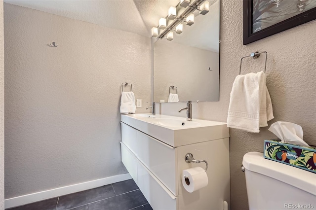 2901 N Glencoe St, Denver, CO 80207 - bathroom with tile patterned flooring, toilet, double vanity, a textured wall, and baseboards