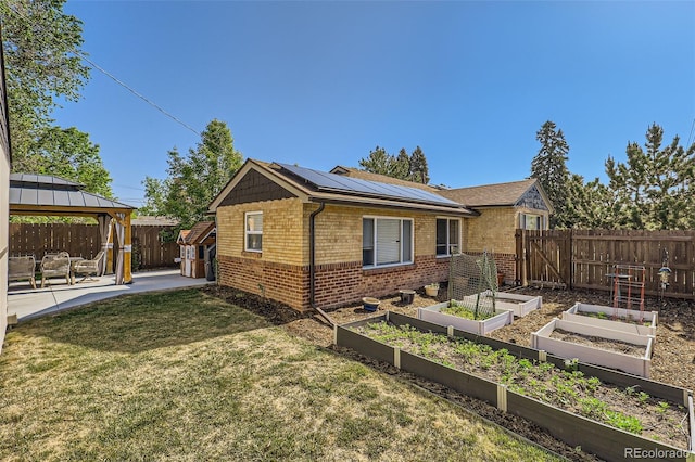 2901 N Glencoe St, Denver, CO 80207 - view of home's exterior with a vegetable garden, brick siding, a gazebo, roof mounted solar panels, and a patio