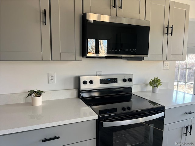 kitchen with gray cabinets, light stone countertops, and stainless steel appliances