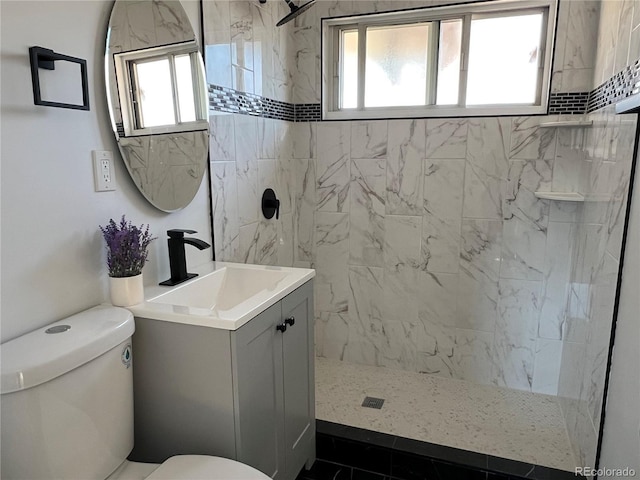 bathroom with a tile shower, tile patterned flooring, vanity, and toilet