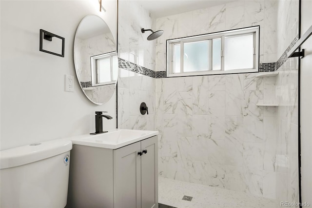 bathroom featuring tiled shower, vanity, toilet, and a wealth of natural light