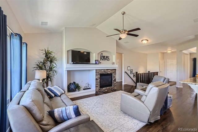 living area with dark wood finished floors, a fireplace, visible vents, vaulted ceiling, and ceiling fan