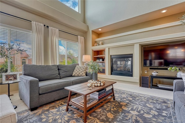 9952 Pinedale Dr, Colorado Springs, CO 80920 - carpeted living room with healthy amount of natural light, a towering ceiling, built in features, a glass covered fireplace, and recessed lighting
