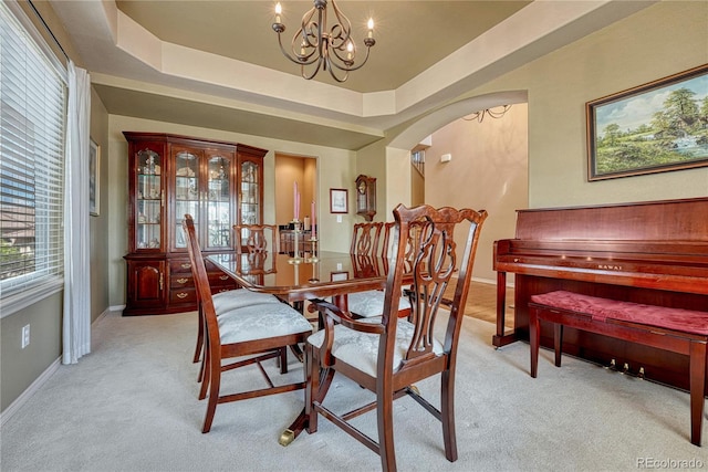 9952 Pinedale Dr, Colorado Springs, CO 80920 - dining room with a chandelier, arched walkways, light carpet, baseboards, and a raised ceiling