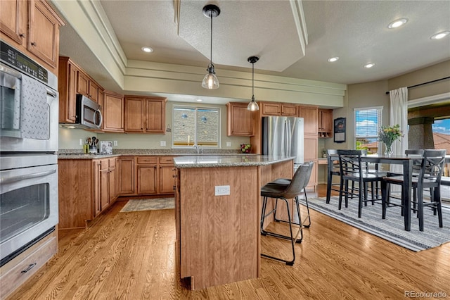 9952 Pinedale Dr, Colorado Springs, CO 80920 - kitchen featuring appliances with stainless steel finishes, a kitchen island, light wood-style floors, a textured ceiling, and recessed lighting
