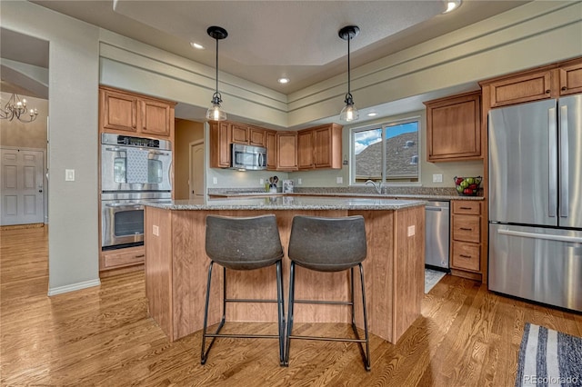 9952 Pinedale Dr, Colorado Springs, CO 80920 - kitchen featuring stainless steel appliances, light wood finished floors, a kitchen island, brown cabinetry, and recessed lighting
