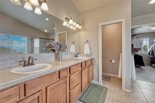 9952 Pinedale Dr, Colorado Springs, CO 80920 - bathroom with vaulted ceiling, a shower stall, a spacious closet, double vanity, and tile patterned flooring