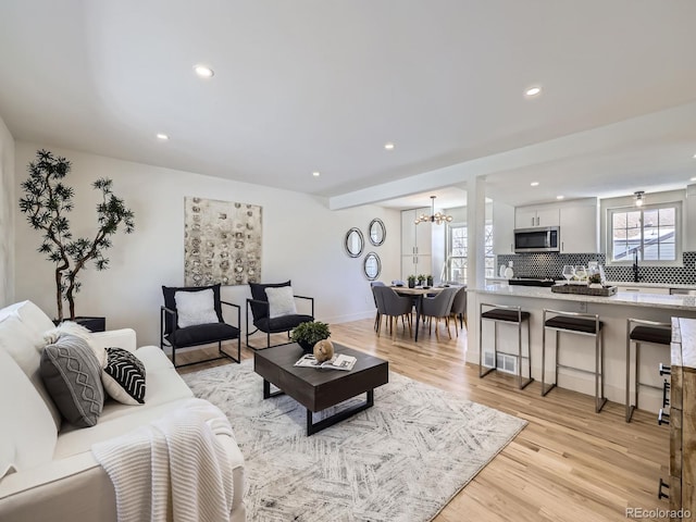 living room featuring a notable chandelier and light wood-type flooring