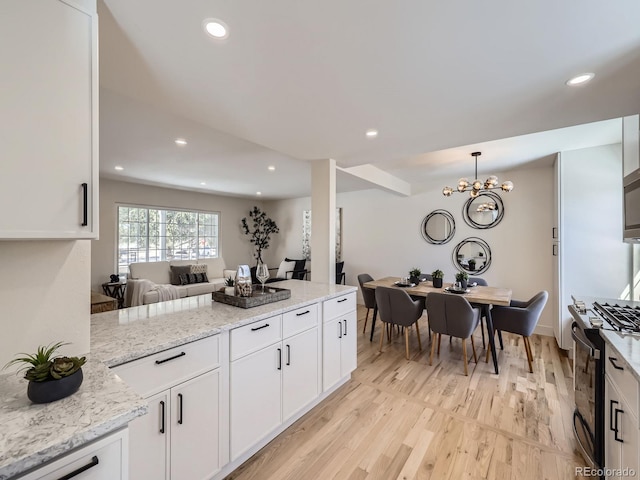 kitchen with light stone counters, pendant lighting, gas stove, and white cabinets