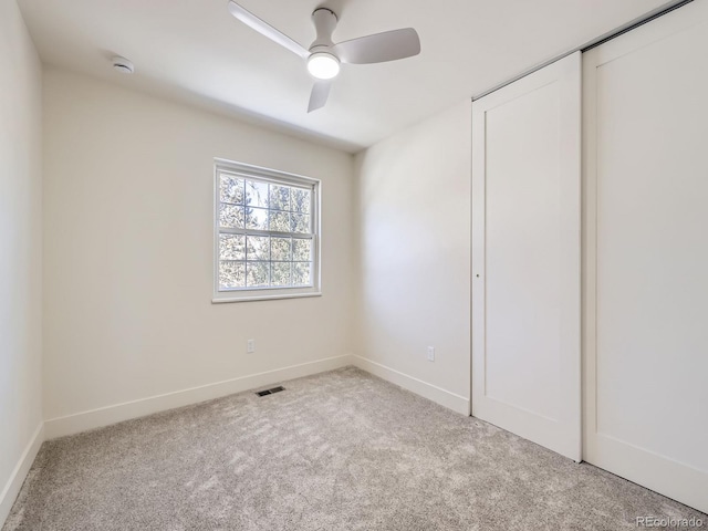 unfurnished bedroom featuring light colored carpet, ceiling fan, and a closet