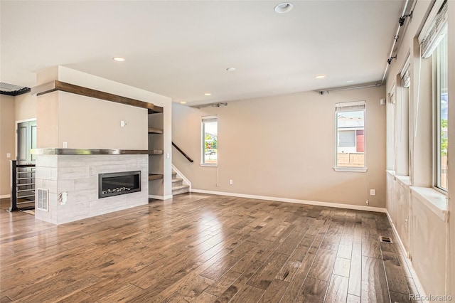 15437 W 95th Ave, Arvada, CO 80007 - unfurnished living room with wood finished floors, a glass covered fireplace, recessed lighting, and stairs