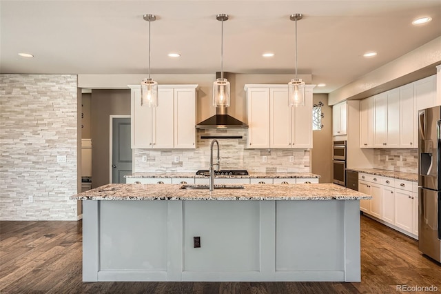 15437 W 95th Ave, Arvada, CO 80007 - kitchen featuring wall chimney exhaust hood, appliances with stainless steel finishes, a center island with sink, light stone countertops, and tasteful backsplash