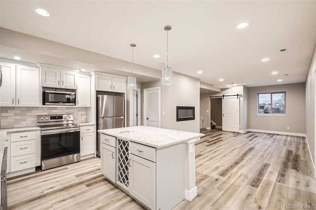 15437 W 95th Ave, Arvada, CO 80007 - kitchen featuring stainless steel appliances, a barn door, backsplash, a center island, and light wood-type flooring