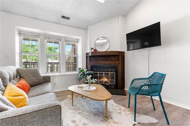 3050 W 107th Pl Unit E, Westminster, CO 80031 - living area with a glass covered fireplace, wood finished floors, baseboards, and a textured ceiling