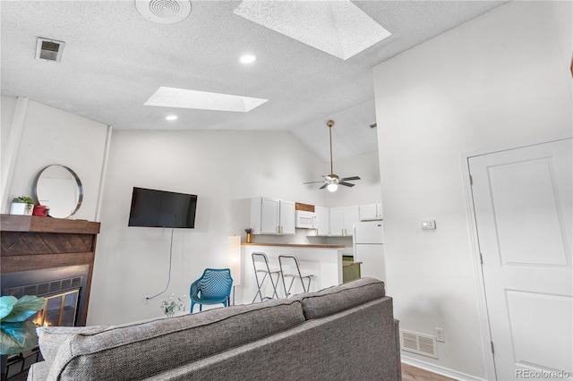 3050 W 107th Pl Unit E, Westminster, CO 80031 - living area featuring a skylight, a glass covered fireplace, baseboards, a textured ceiling, and wood finished floors
