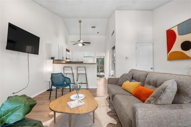 3050 W 107th Pl Unit E, Westminster, CO 80031 - living area featuring high vaulted ceiling, light wood-type flooring, ceiling fan, and baseboards