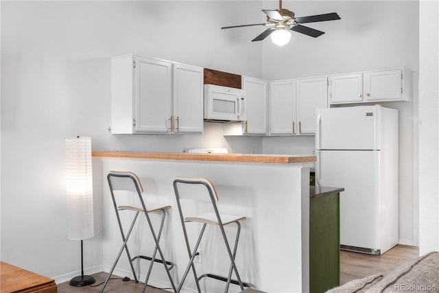 3050 W 107th Pl Unit E, Westminster, CO 80031 - kitchen with white appliances, ceiling fan, white cabinetry, a kitchen breakfast bar, and a towering ceiling