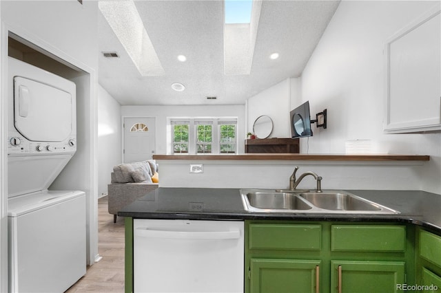 3050 W 107th Pl Unit E, Westminster, CO 80031 - kitchen with dishwasher, a sink, stacked washer and clothes dryer, open floor plan, and dark countertops