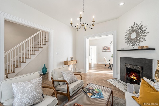 living room featuring stairs, a chandelier, a fireplace with flush hearth, wood finished floors, and recessed lighting