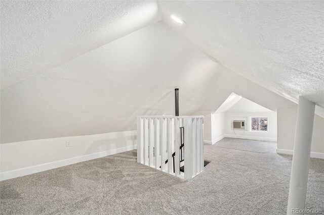 additional living space with carpet flooring, a textured ceiling, baseboards, and lofted ceiling