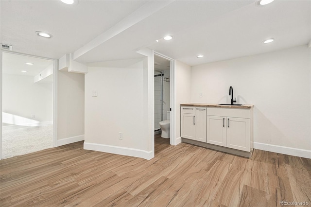 bar area featuring baseboards, light wood-style floors, a sink, and recessed lighting