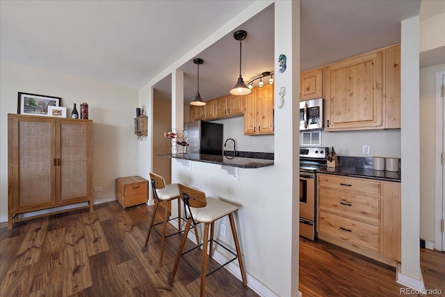 kitchen featuring pendant lighting, light brown cabinets, appliances with stainless steel finishes, kitchen peninsula, and a breakfast bar area