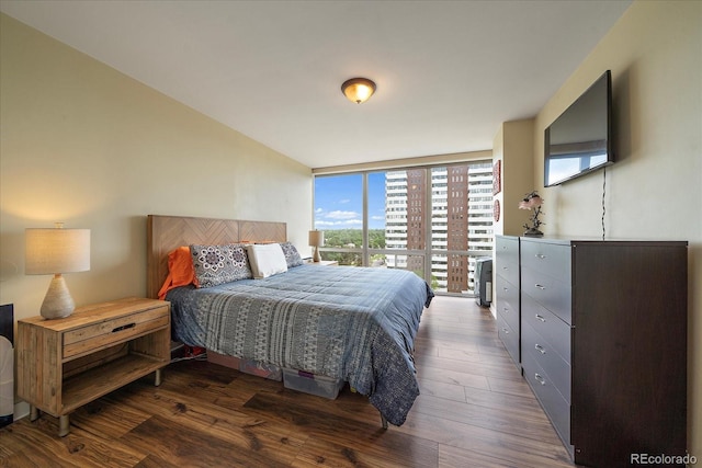 bedroom with expansive windows and dark wood-type flooring