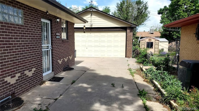 exterior space with an outbuilding, brick siding, concrete driveway, central AC unit, and a shed