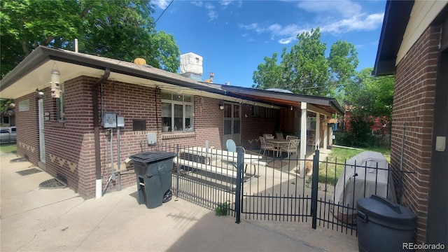 rear view of property with fence, brick siding, a chimney, and a patio area