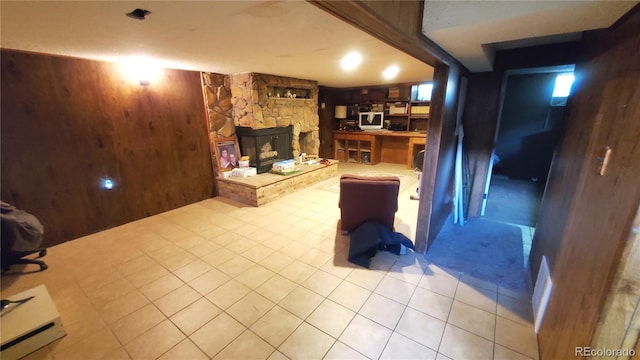 living room featuring wooden walls and a stone fireplace