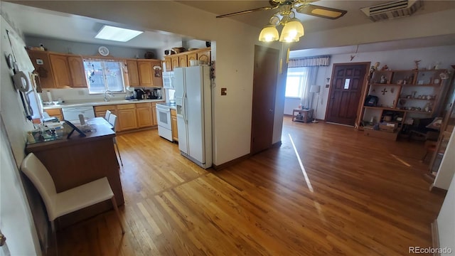 kitchen featuring light countertops, white appliances, a sink, and light wood-style flooring