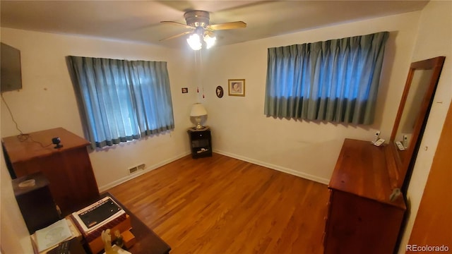 bedroom featuring a ceiling fan, wood finished floors, visible vents, and baseboards