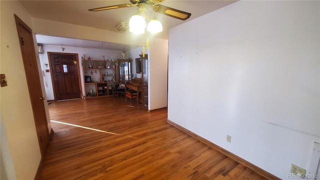 interior space with a ceiling fan, baseboards, and wood finished floors