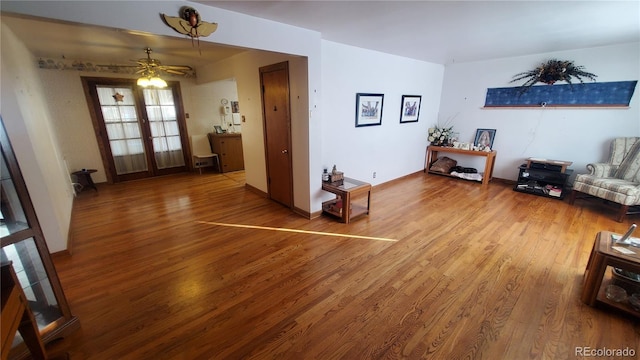 living room with wood finished floors, baseboards, and ceiling fan