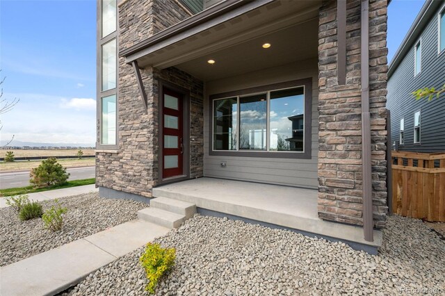 entrance to property featuring stone siding and fence