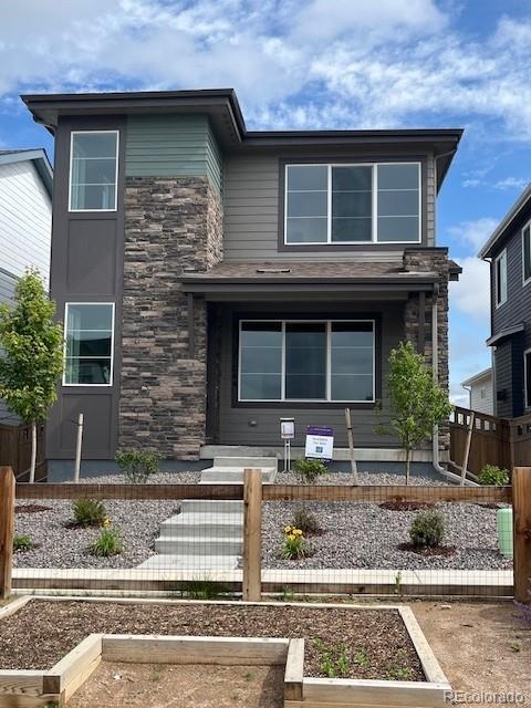 21044 E 63rd Dr, Aurora, CO 80019 - modern home with stone siding, a fenced front yard, and a vegetable garden
