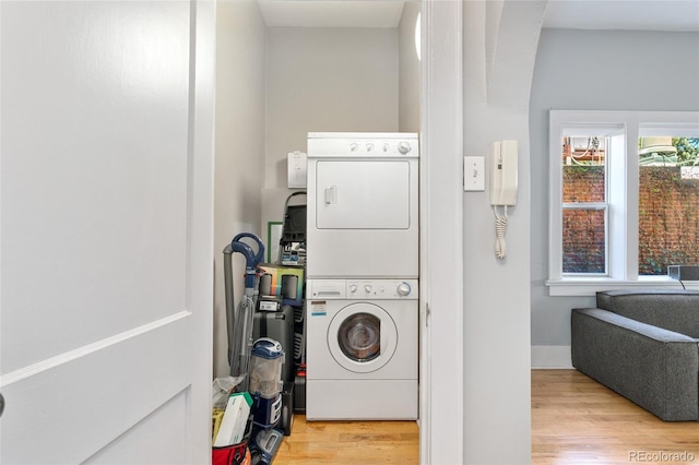 laundry area with laundry area, wood finished floors, and stacked washing maching and dryer