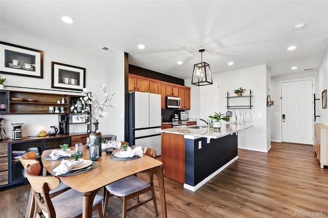3699 Makley Cir, Castle Rock, CO 80104 - kitchen with stainless steel appliances, a sink, recessed lighting, wood finished floors, and a kitchen island with sink